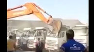 ببینید / حمله جنون راننده بیل‌مکانیکی به کامیون‌ها! + فیلم