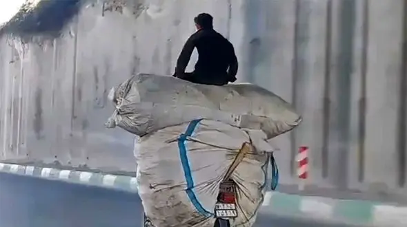 ببینید /حرکت خطرناک یک موتورسوار برای حمل بار زیاد در خیابان‌های تهران