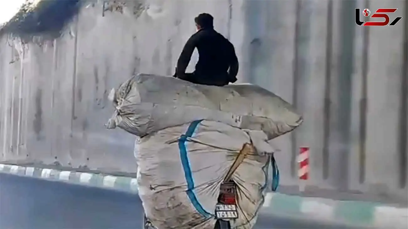 ببینید /حرکت خطرناک یک موتورسوار برای حمل بار زیاد در خیابان‌های تهران