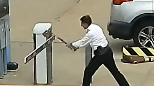 ببینید / حمله جنون‌آمیز خلبان به گیت پارکینگ با تبر؛ لحظه دستگیری توسط پلیس!