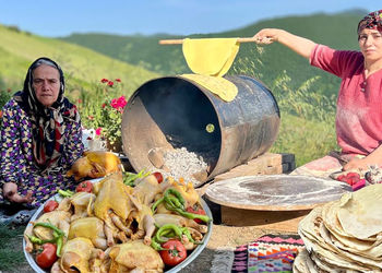 غذای روستاهای گیلان؛ پخت مرغ بریانی در بشکه و نان تازه + فیلم