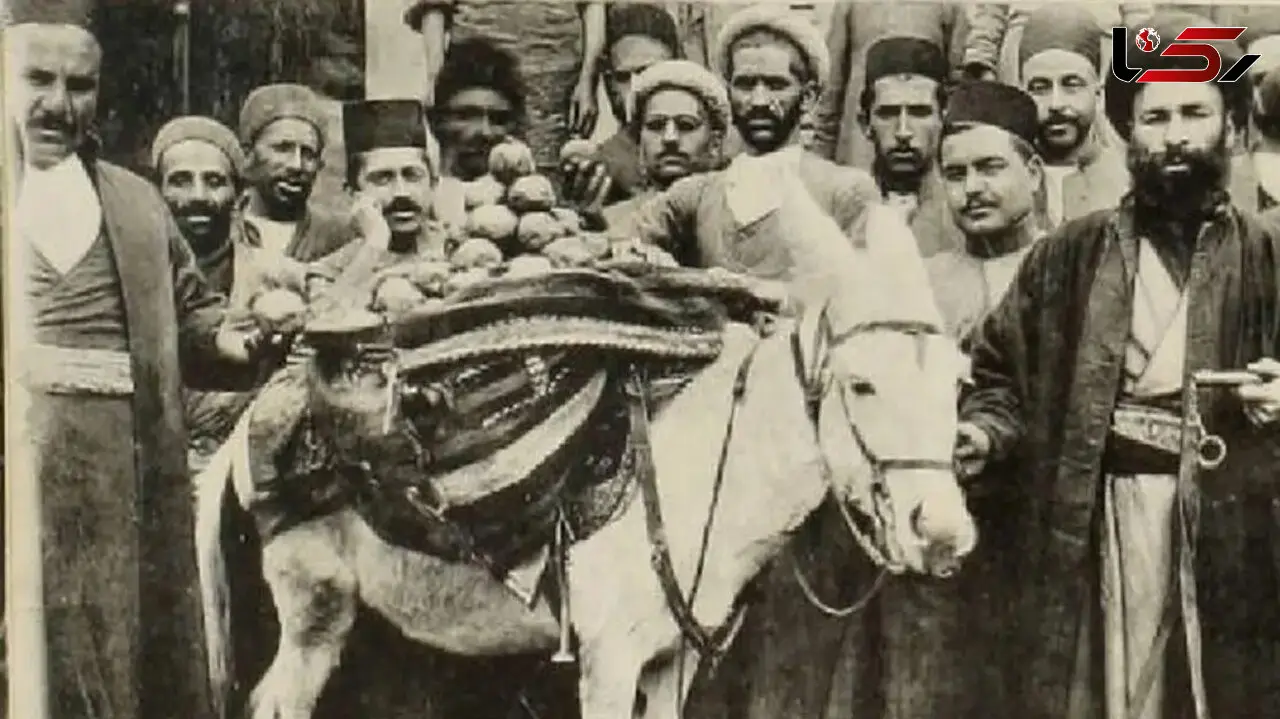عکس سفر زمان /  مرد بار فروش با الاغ اش در حال عبور از خیابان فردوسی تهران و جلوی صرافی کوروش؛ سال 50
