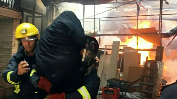 عکسی تاثیرگذار و جالب / نحوه نجات پیرزن گرفتار آتش سوزی توسط آتش نشان تبریزی