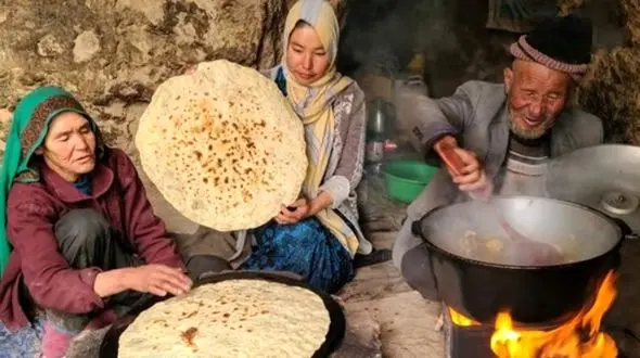 فیلم/ پخت نان روی ساج و آبگوشت مرغ توسط خانواده غارنشین