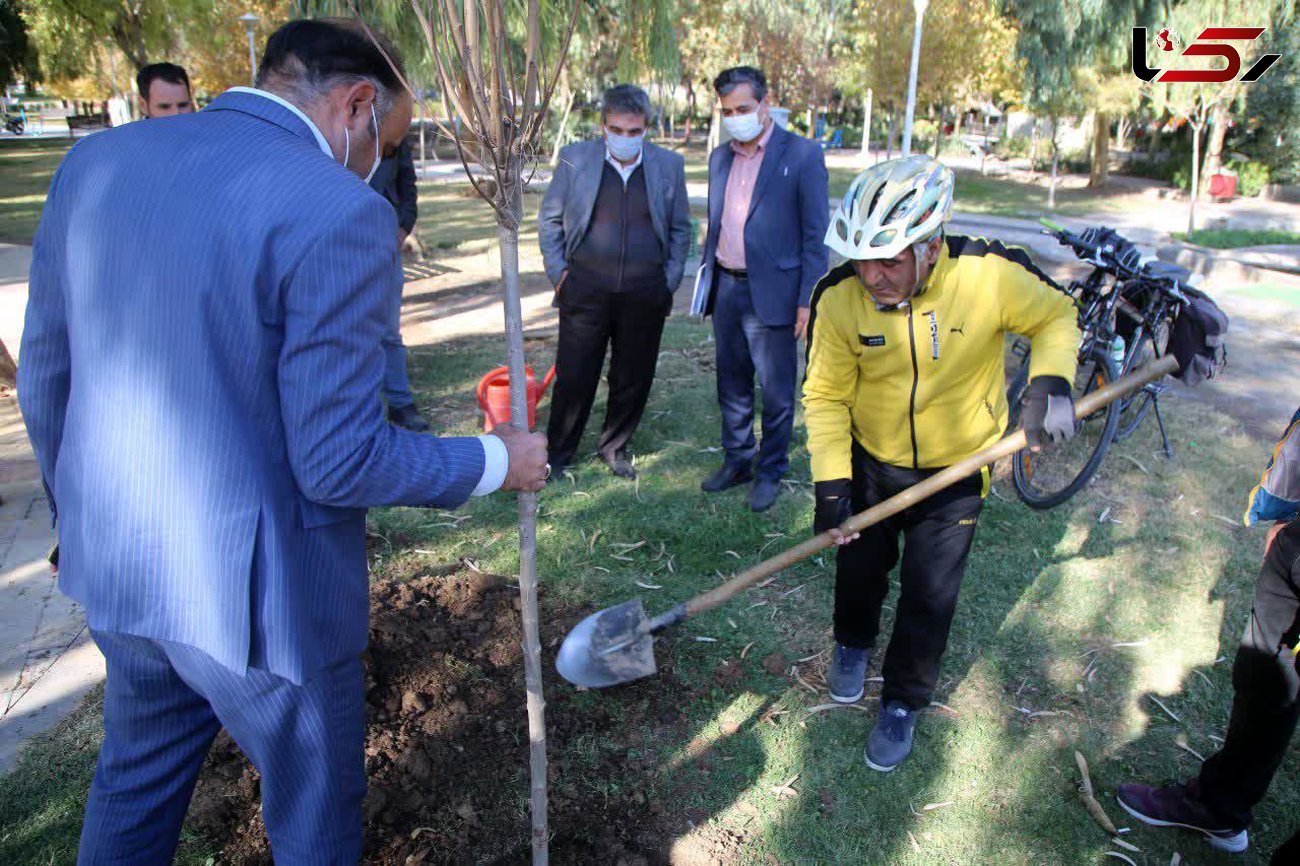 کاشت نمادین نهال توسط توریست دوچرخه‌سوار در بوستان شهید بنیادی قم