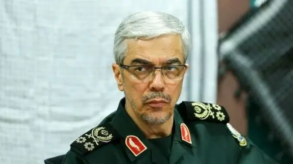 عکس سفر به تاریخ / «سپهبد باقری» در یک منطقۀ جنگی در سوریه در حال بررسی نقشۀ نظامی