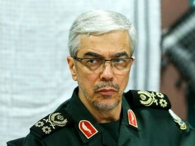 عکس سفر به تاریخ / «سپهبد باقری» در یک منطقۀ جنگی در سوریه در حال بررسی نقشۀ نظامی