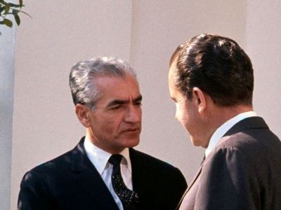 عکس سفر در زمان / شاه پهلوی در حال کمک به ملکه الیزابت برای پیاده شدن از کالسکه در تهران / سال 1338