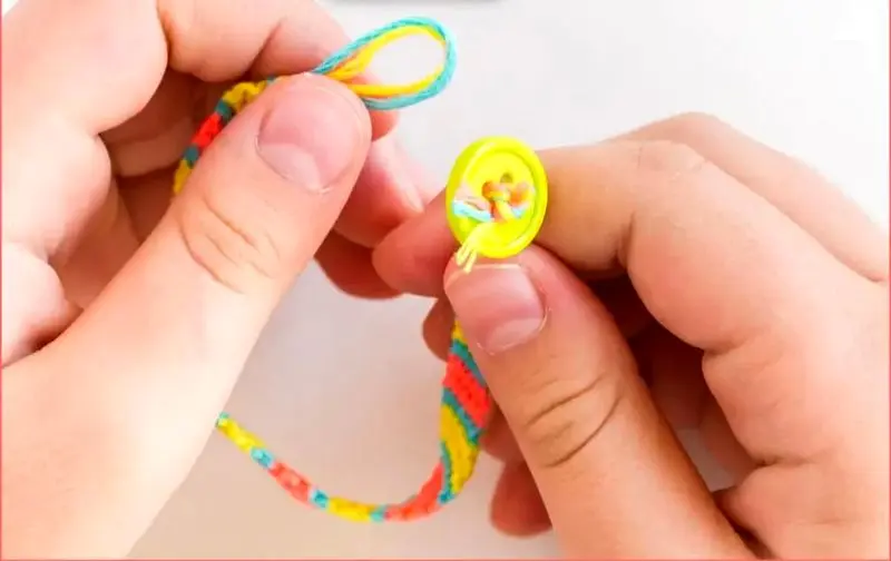 مراحل بافت دستبند رنگی با نخ‌های کاموایی روی تخته کار