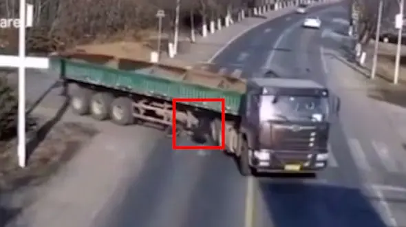 مرد جوان با دوچرخه اش زیر تریلی له شد اما زنده ماند + فیلم شوک آور