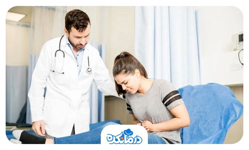 یک خانم روی تخت بیمارستان نشسته و دل خود را فشار می‌دهد. پزشک در کنار او ایستاده و بیمار را معاینه می‌کند.